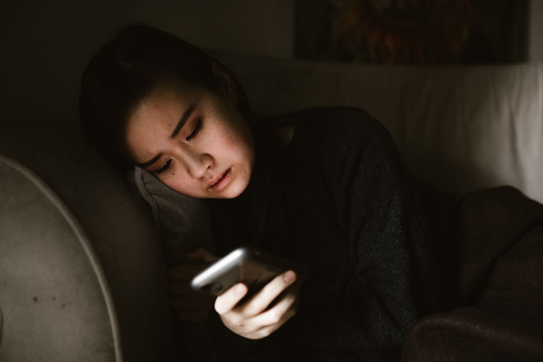 Mujer mirando el móvil de noche con expresión preocupada, buscando información sobre sus síntomas de ansiedad