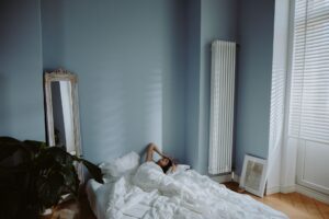 Mujer relajada sobre una cama en un dormitorio sereno con luz natural