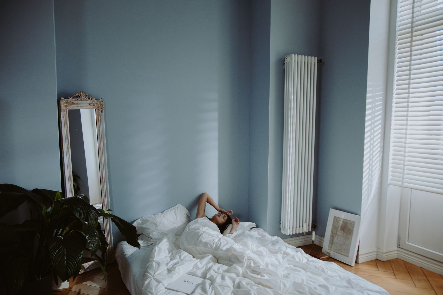 Mujer relajada sobre una cama en un dormitorio sereno con luz natural